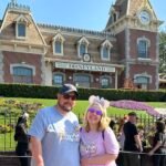 Ryan and his wife standing in front of the train station at Disneyland